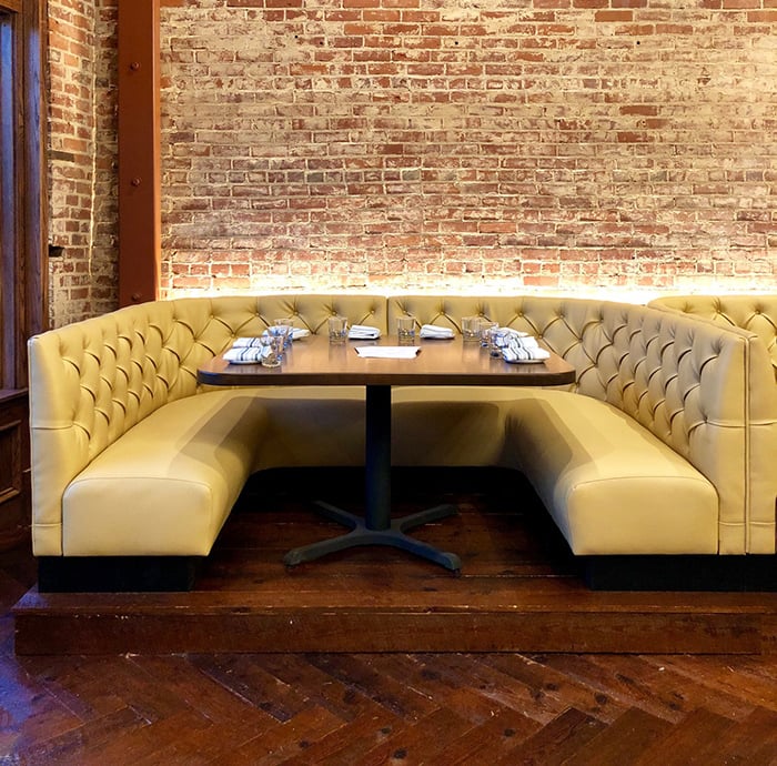 Charlotte-NC-detailed-view-of-a-u-shaped-restaurant-booth-with-cream-leather-tufted-cushion